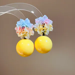 Detailed macro view of resin flower earrings featuring vibrant gradient petals and yellow bead