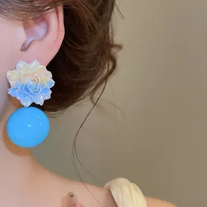 Detailed close-up of vibrant blue resin flower earrings with a large glossy sphere drop.