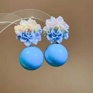 Close-up detail of dopamine resin gradient flower stud earrings with large sky blue spheres