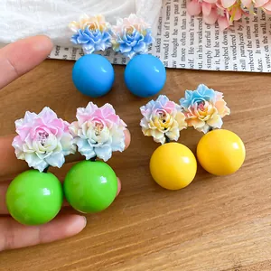 Close-up detail of vibrant resin flower and ball stud earrings for a sweet vacation style
