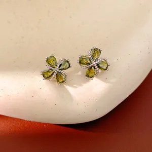 Primer plano de pendientes de trébol con circonitas verde oliva y baño de oro de 18 quilates