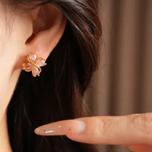 Detalle de elegantes pendientes de trébol en oro de 18k con circonitas rosas en la oreja.