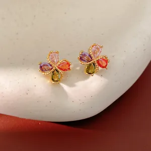 Primer plano detallado de pendientes de trébol con piedras de circonita de colores