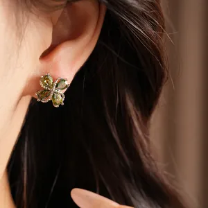 Vista detallada de pendientes de trébol bañados en oro de 18k con circonitas verdes