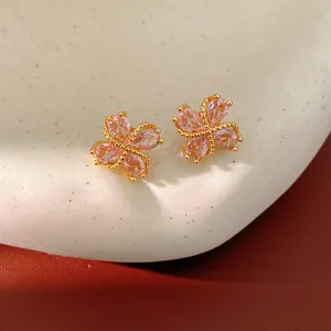 Macro de pendientes de flor de circón rosa bañados en oro de 18 quilates sobre textura