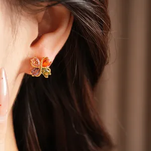 Primer plano detallado del pendiente de trébol de circonita multicolor en una oreja