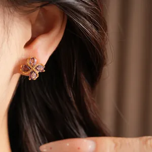 Detalle de un elegante pendiente de trébol bañado en oro de 18k con circón púrpura fino