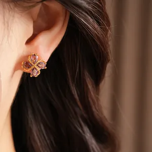 Primer plano detallado de elegantes pendientes de trébol con circonitas moradas en la oreja