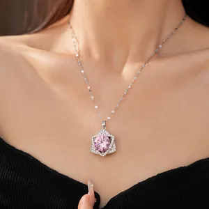 Detail view of a silver necklace with a pink star-shaped zircon pendant on a model.