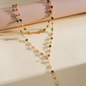 Détail d'un collier en Y doré orné de cristaux multicolores et de petits cœurs dorés.