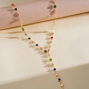 Gros plan d'un collier doré avec des cristaux colorés et des breloques en cœur