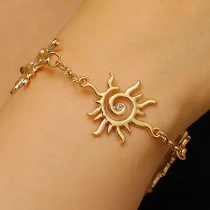 Dettaglio di un bracciale dorato con motivo a spirale solare e cristallo centrale