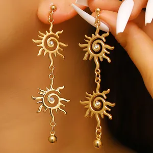 Primo piano di orecchini pendenti dorati a forma di sole bohémien con un brillante strass al centro.