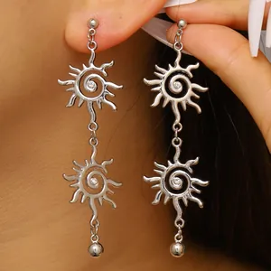 Dettaglio macro di orecchini pendenti color argento con motivo a vortice solare e piccoli strass