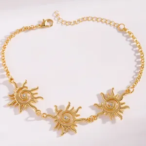 Dettaglio di una collana a spirale solare dorata con motivi etnici e piccoli cristalli