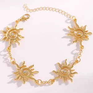 Dettaglio del bracciale dorato con ciondoli a spirale solare e piccoli cristalli