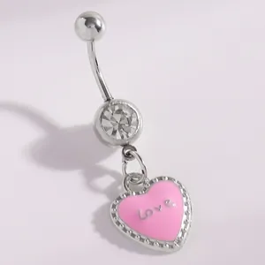 Close-up of a silver belly button ring with a pink heart pendant and clear rhinestone