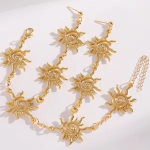 Dettaglio del set di gioielli con sole a spirale dorato, orecchini e collana boho.