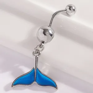 Close-up of a silver belly button ring with a vibrant blue enamel whale tail pendant.