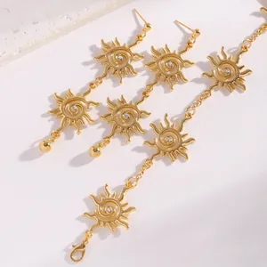 Dettaglio macro di orecchini e collana vintage a spirale solare dorata con cristalli.