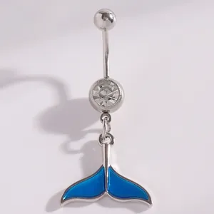 Close-up of silver navel ring with sparkling clear stone and blue whale tail charm