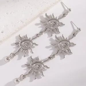 Primo piano di orecchini pendenti a sole con vortice argentati e cristalli stile etnico.
