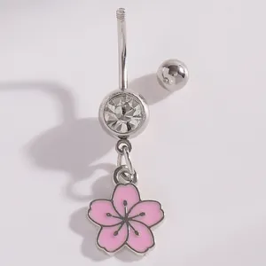 Close-up detail of silver belly button ring with pink cherry blossom flower pendant