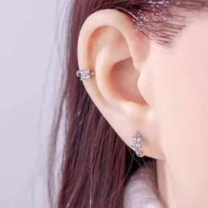 Dainty silver four-petal zircon flower ear cuff and hoop earrings worn on a model's ear