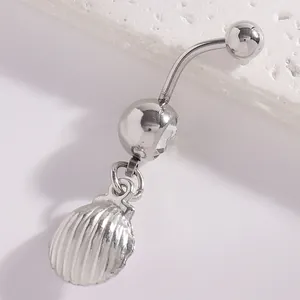 Close-up of a silver shell pendant navel ring on a white textured stone surface