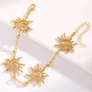 Dettaglio macro dei ciondoli a vortice di sole dorati con centri in cristallo brillanti.