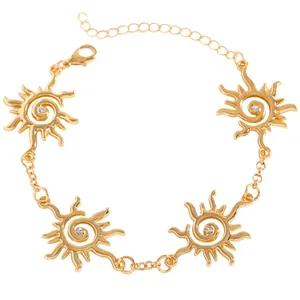 Dettaglio di bracciale dorato a forma di sole con cristallo e chiusura a moschettone
