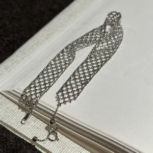Nahaufnahme eines silbernen Metallarmbands mit filigranem Hohlnetz-Design und Struktur