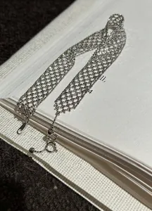 Detailaufnahme eines silbernen Metallarmbands mit einem ausgehöhltem Gittermuster