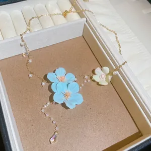 Close-up detail of blue fabric flowers and delicate pearls on a gold-tone necklace