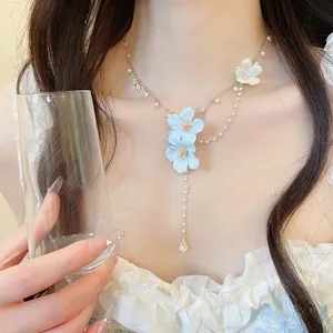Close-up of a dreamy fairy-style necklace with blue fabric flowers, pearls, and crystals.