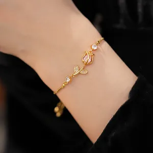 Detail shot of golden tulip bracelet with pink zircon flower on model's wrist