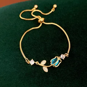 Detailed view of a gold tulip bracelet with a blue zircon flower bud on green velvet