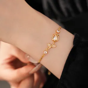 Close-up of elegant gold-toned bracelet featuring a zircon-encrusted tulip design on a wrist