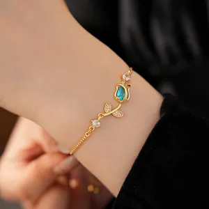 Close-up of an elegant gold-tone tulip bracelet with a blue teardrop zircon stone