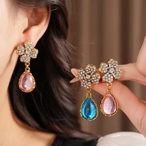 Detail view of vintage flower earrings with rhinestones and colorful resin pendants.