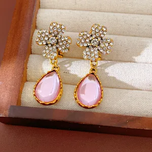 Close-up of vintage crystal flower earrings with elegant pink resin teardrop dangles