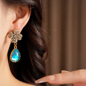 Close-up of vintage flower earrings featuring brilliant blue teardrop resin pendants