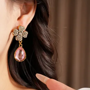 Detail view of vintage rhinestone flower earrings featuring a pink resin teardrop pendant
