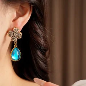 Vintage gold flower stud earrings with sparkling rhinestones and blue resin teardrop.