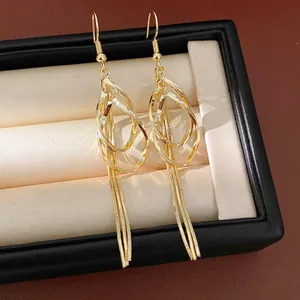 Macro detail view of elegant gold-toned teardrop earrings featuring long chain tassels