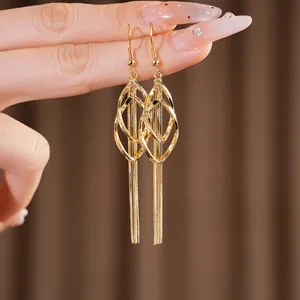Close-up of elegant gold waterdrop geometric tassel earrings held by hand for jewelry detail