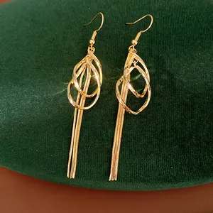 Close-up of gold waterdrop geometric hollow earrings with long tassel chains on green velvet
