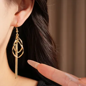 Close-up detail showing elegant golden teardrop earrings with long chain tassels