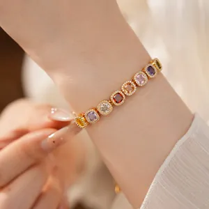 Elegant close-up of a gold bracelet featuring multi-colored square zircon stones on wrist