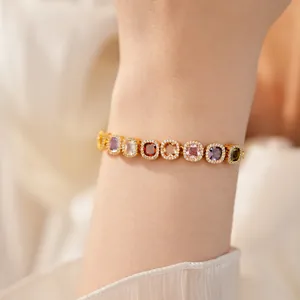 Close-up of elegant gold bracelet featuring colorful square zircons on a model's wrist